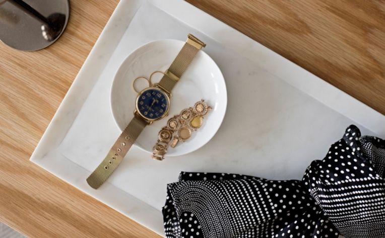 flatlay photo of a tray with a dish containing a watch, bracelet, and earrings